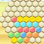 A colorful hexagonal puzzle board featuring variously colored tiles, including yellow, blue, pink, and green, arranged on a sandy background, ideal for a game or activity