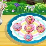 A colorful plate with cartoon animal-shaped cookies arranged in a circle, accompanied by a milkshake in a glass, set against a vibrant outdoor garden background with flowers