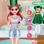 A young girl wearing a striped shirt and denim shorts stands next to a selection of green dresses and accessories, alongside a green top hat, set in a cozy bedroom environment