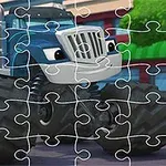 A partially completed jigsaw puzzle featuring a cartoon blue monster truck, set against a colorful background with buildings and greenery