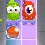 The image features two cute cartoon-like characters, a green one with big eyes and a red one with one large eye, positioned on a shelf next to a shiny orange ball, set against a colorful, tiled background