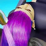 A woman with vibrant purple hair is reclining in a salon chair while water from a shiny faucet washes her hair, set against a bright blue background