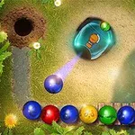 A colorful puzzle game scene featuring a shooting mechanism aimed at a chain of multicolored balls, set in a lush, green environment with a river and flowers in the background