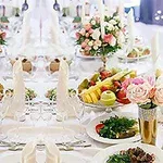 A beautifully arranged dining table with elegant floral centerpieces, assorted fruits, and gourmet dishes, set for a formal event