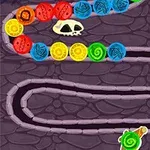 A colorful, curved pathway featuring vibrant balls of different colors, a skull, and spiked obstacles on a dark, stone-textured background, resembling a whimsical game level