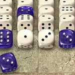 A collection of white and blue dice arranged in rows on a textured background, featuring both standard six-sided dice and colored dice with distinct designs