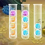 Four clear test tubes filled with colorful round creatures, featuring pink, orange, and blue variations, set against an underwater background with vegetation and treasure