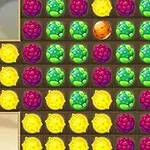 The image features a colorful grid game layout with various fruit-themed icons, including yellow lemons, green fruits, purple berries, and a central orange fruit, set against a light background