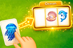 A hand moves a jellyfish card toward glowing ocean-themed cards with a shell and dolphin on a green background