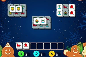 A colorful holiday-themed Mahjong game layout featuring tiles with various Christmas symbols like bells, stockings, and ornaments against a snowy blue background